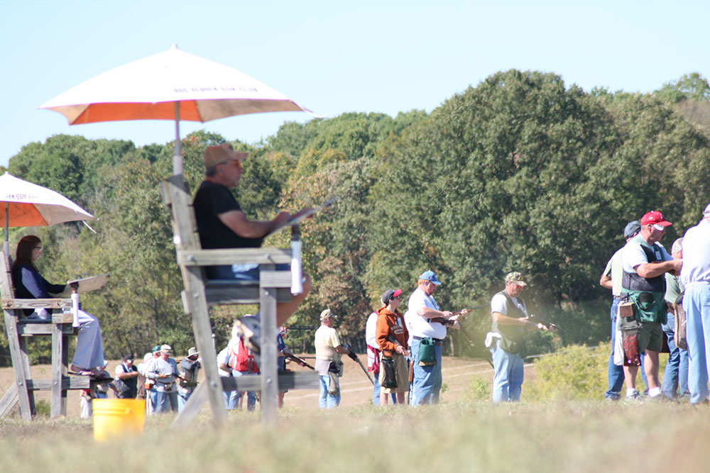 Shooters lined up on the trap fields under orange umbrellas